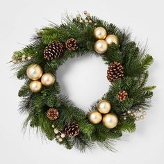 a christmas wreath with gold ornaments and pine cones on white background, top view stock photo