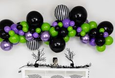 the balloon wall is decorated with black, purple and green balloons for an elegant halloween party