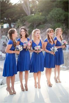 a group of women in blue dresses standing next to each other on a cell phone