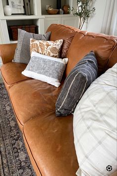 a brown leather couch with several pillows on it