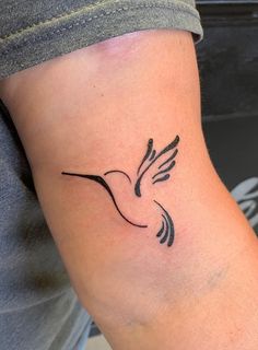 a small black and white bird tattoo on the right side of the left arm,