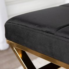 a close up of a black and gold bench with white rugs on the floor