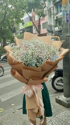 a woman holding a large bouquet of flowers on the street