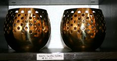 two shiny gold vases sitting on top of a wooden shelf next to each other