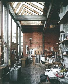 a room filled with lots of clutter and furniture next to a brick wall covered in windows