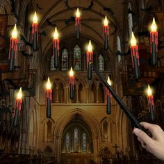 a person holding a wand in front of a church with candles hanging from the ceiling