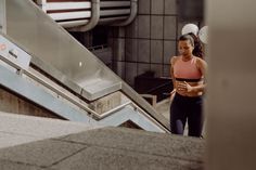 a woman is walking down an escalator