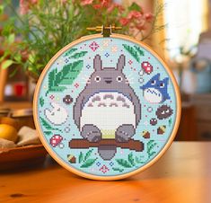 a cross stitch totoro sitting on top of a wooden table