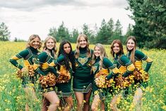 a group of women in cheerleader outfits posing for a photo on a field with yellow flowers