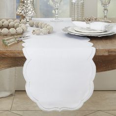 the table is set with silver and white dishes, candles, and napkins on it