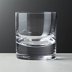 an empty glass sitting on top of a white counter next to a gray wall and floor