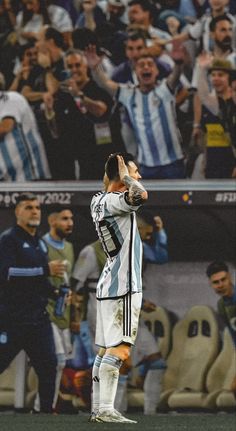 a man standing on top of a soccer field holding his hands up in the air