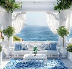 an outdoor living area with white furniture and blue rugs on the floor, overlooking the ocean