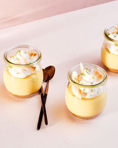 three small jars filled with dessert sitting on top of a table