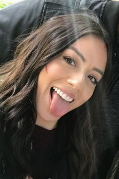 a woman sticking out her tongue while laying on the ground in front of a black jacket