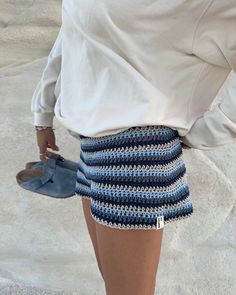 a woman wearing blue and white crocheted shorts with her hand on her hip