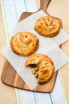 three pies sitting on top of a wooden cutting board