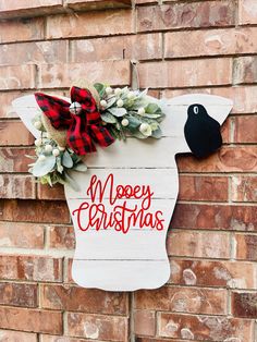 a wooden sign that says merry christmas hanging on the side of a brick wall next to a black bird