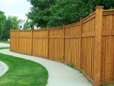 a long wooden fence next to a sidewalk