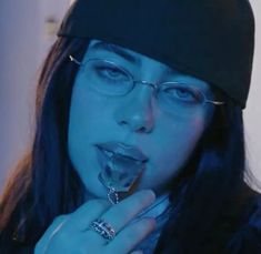 a woman wearing glasses and a beanie is making a funny face with her finger