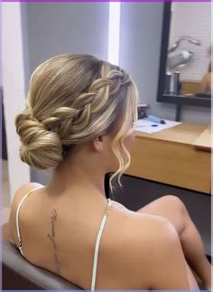 a woman sitting in a chair with her back turned to the camera and braided hair