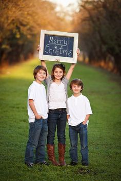 three children holding up a chalkboard with the words merry christmas written on it in front of them