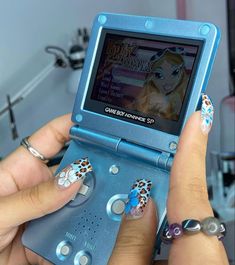 a person holding up a gameboy with designs on it's screen and hands