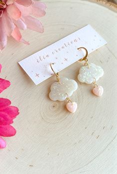 the earrings are on display next to a pink flower