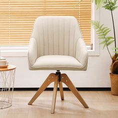 a white chair sitting on top of a wooden table next to a window with blinds