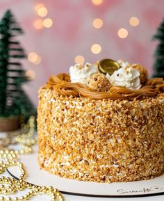 a cake with white frosting and gold sprinkles on it, surrounded by christmas trees