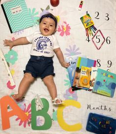 a baby laying on top of a blanket next to some books and other items in front of him