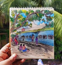 a hand holding up a drawing of people waiting at a train station for their next ride