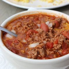 two bowls of chili and cornbread soup on a table with other dishes in the background