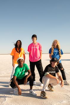 four young people posing for a photo in the snow with one person on his knees