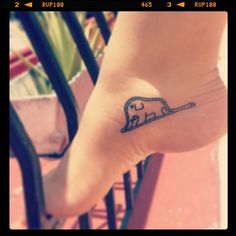 a small elephant tattoo on the foot of a woman's foot, with an arrow