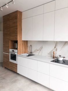 a kitchen with white cabinets and marble counter tops, along with a stove top oven