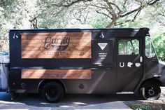 the food truck is parked on the side of the road in front of some trees