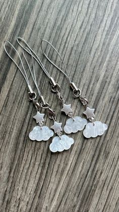 four silver stars and clouds dangling earrings on a wooden surface