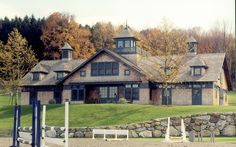 a large house sitting on the side of a lush green field next to a forest