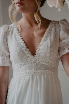 a woman wearing a white dress and holding flowers in her hand with the back of her head