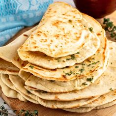 a stack of pita bread sitting on top of a wooden cutting board