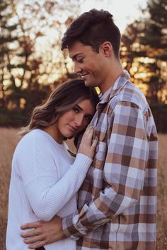 a young man and woman embracing each other in an open field