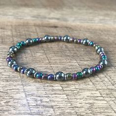 Check out this showstopper! The beautiful metallic jewel tone colors of the hematite beads are striking against the black and silver stainless steel. #elasticbracelet #stretchbracelet #mysticjewelry #handmadejewelry #hematitebracelet #beadedbraceletsforwomen #uniquestyle #giftforher #loralyndesigns Elastic Bead Bracelet, Bracelets Bead, Iridescent Black, Mystical Jewelry, Jewel Tone Colors, Calm Your Mind, Hematite Bracelet, Hematite Beads, Elastic Bracelet