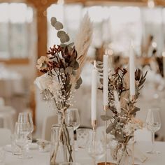 there are candles and flowers on the table at this wedding reception with tall centerpieces