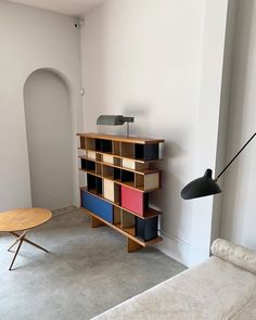 a living room with a couch, coffee table and book shelf in the corner on the wall