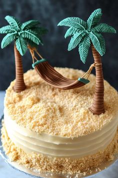 a cake decorated with coconut trees and hammock on it's top is sitting on a glass platter