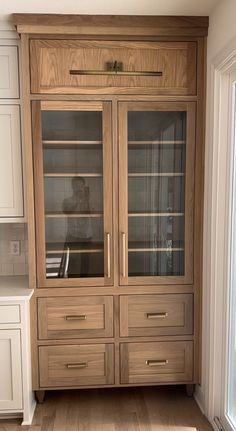 a wooden cabinet with glass doors in a kitchen