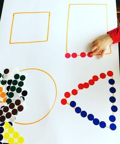 a child's hand on a piece of paper with circles and shapes