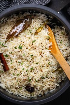 a bowl filled with rice and spices next to a wooden spoon