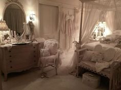 a bedroom with white bedding and lots of pillows on the floor next to a dresser